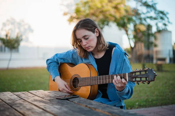 휴대폰으로 악보를 읽으면서 기타치는 즐기는 그녀는 피크닉 지역에 있습니다 — 스톡 사진