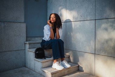 Ciddi bir kadın merdivenlerde otururken telefonda hararetli bir konuşma yapıyor..