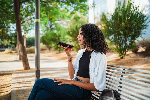 Afrikalı genç bir kadın bir arkadaşına sesli mesaj gönderiyor. Akıllı telefonunu kullanıyor..