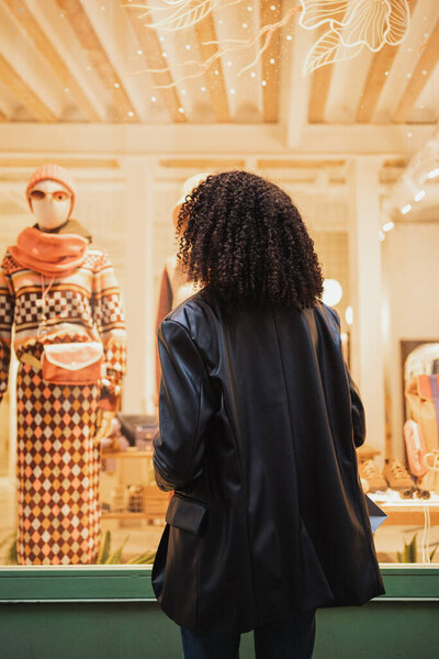 Выстрел девушки сзади. Она смотрит в витрину магазина, чтобы купить новое платье.