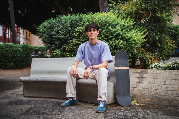 Portrét Skateboardisty Jak Dívá Kamery Sedí Lavičce Uprostřed Města — Stock fotografie
