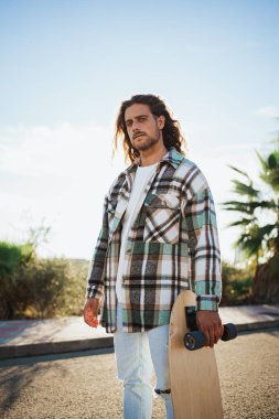 Kameraya bakan bir patencinin portresi. Arka planda palmiye ağaçları ile caddede.