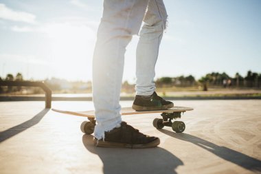 Kaykayın üzerinde kaykaycı ayaklarının arka ışıklandırması. Ata binmek üzere.