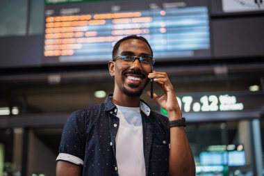 Tren istasyonunda beklerken Afrikalı bir erkek telefonda konuşuyor.