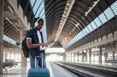 Afrikalı gezgin tren istasyonunda beklerken haritaya bakıyor.