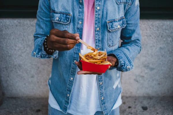通りでおいしいフライドポテトを食べて立っている匿名の男の高角度ショット — ストック写真