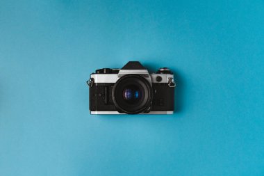 Mavi arkaplandaki eski film kamerasının yüksek açılı görüntüsü. Film fotoğrafçılığı kavramı.