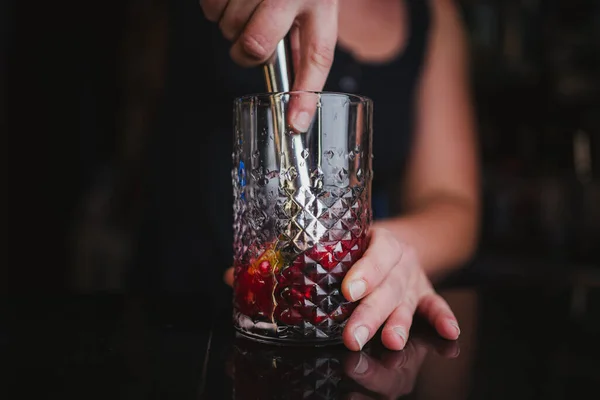 居酒屋のバーで果物モヒートを作るためにマドラーを使用してライムやベリーを粉砕女性バーテンダー — ストック写真