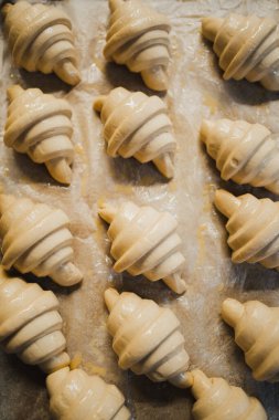 Fırında pişmemiş taze kruvasanların üst düzey görüntüsü.