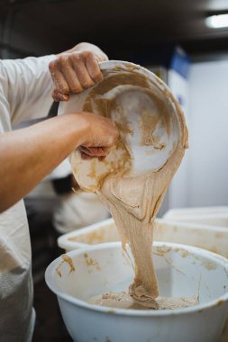 Fırıncı adam taze ve yapışkan ekmek hamurunu bir alıcıdan diğerine taşıyor.
