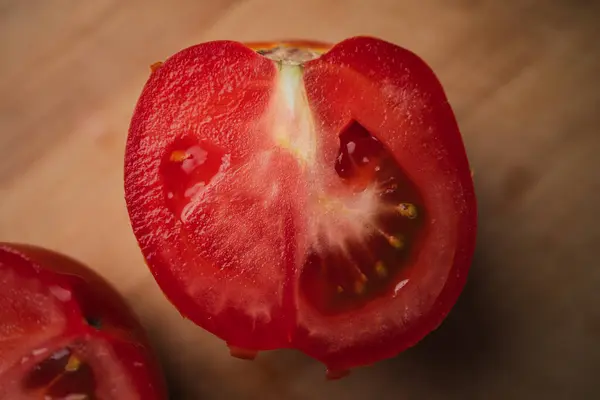 stock image Close up of a tomato cut in half on a wooden table. Spanish breakfast preparation.