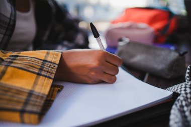 Ders çalışmak için not defterine yazan öğrenci kıza yakın çekim. Üniversite kampüsünde..