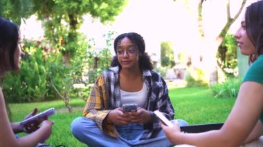 Gülen kolej öğrencileri, çimde oturup, derslere ara veriyorlar..