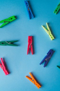 Mavi arka planda bir sürü farklı renkli mandalların üst görüntüsü. Çamaşır konsepti.