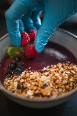 Yabanmersini ve kiviyle acai kasesine ahududu döküyorum. Brunch hazırlığı..