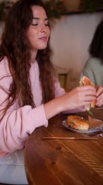 Modern bir kahvecide simitli sandviç yiyen güzel bir genç kadın..