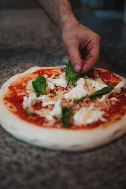 Taş fırına girmeden önce lezzetli bir pizza pişireceğim. Fesleğen ekliyor..