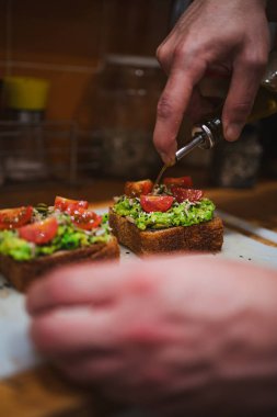 Şili 'deki özel bir kafeteryada sağlıklı ekşi ekmeğin üzerine zeytinyağı döken bir adam..