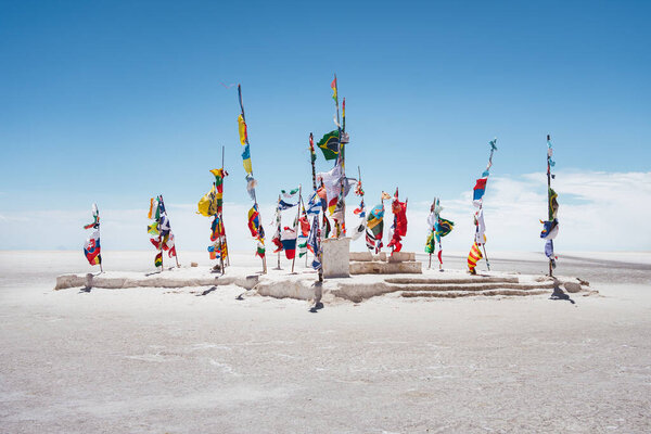 Международные флаги у памятника Дакару на солончаках Салар-де-Уюни в Боливии