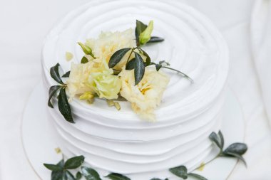 Sarı çiçekler ve yeşil yapraklarla süslenmiş beyaz pasta..