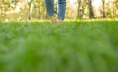 Kırsal bir alanda çıplak ayakla toprağa ve çimenlere dokunmak. Topraklama, sadelik, doğal yaşam tarzı ve huzurlu kırsal yaşamın sembolü..