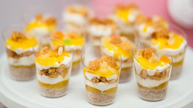 Krema, bisküvi parçacıkları ve meyve sosuyla kaplı mini tatlı fincanları bir parti ya da etkinlik için güzelce servis edilir..