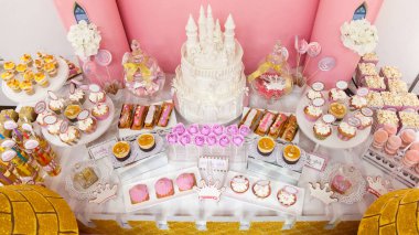 Hassas dantel desenleri ve pastel yeşil şeker çiçekleriyle süslenmiş zarif, beyaz bir düğün pastası. Pastada karmaşık inci ayrıntıları ve gerçekçi yapraklar var.