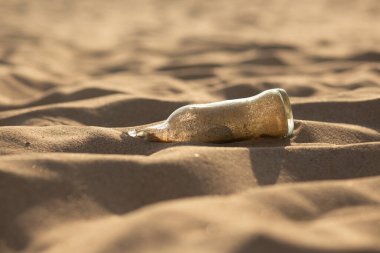 Kırık cam şişenin Macro fotoğrafı. Kuma gömülmüş. Çevre kirliliğinin ve ihmalkarlığının güçlü bir görsel sembolü olarak hizmet veriyor..