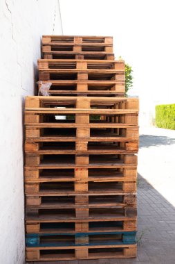 Beyaz sanayi duvarına dayalı ahşap paletler. Lojistik, nakliye ve deponun sembolü..