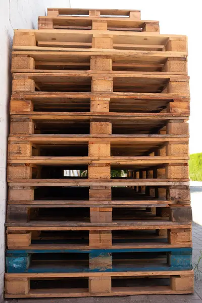 Doğal ahşap, yeniden kullanılmış ve geri dönüştürülmüş lojistik materyal kavramı arasında mavi boyanmış tabanı gösteren paletler yığını.