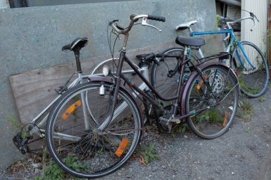 Duvara yaslanmış bir grup eski bisiklet, pas ve terk edilmişlik belirtileri gösteriyor..