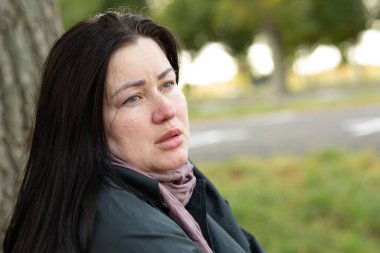 Gözlerinde hüznü gösteren atkı ve paltolu bir kadının yakın plan portresi..