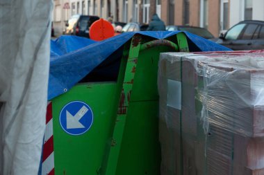 İnşaat alanında mavi ok işareti ve mavi muşamba olan yeşil metal konteynır ayrıntıları.