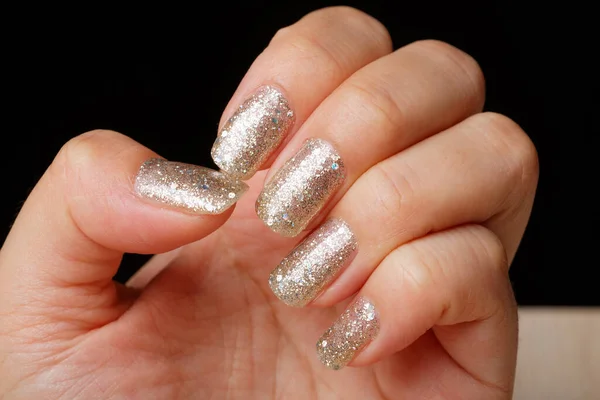 Closeup woman nail with fresh glitter manicure on the black background