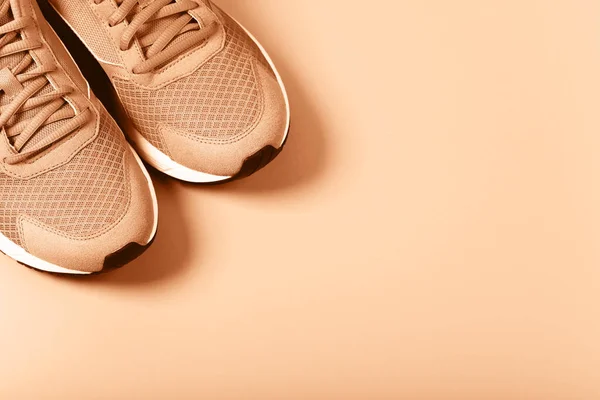 米色背景的桃色运动鞋 健康生活的概念 日常训练和意志力 图库图片
