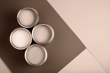 Kahverengi ve bej arkaplan üzerine dizilmiş dört boya kutusunun yukarıdan görünüşü. Kompozisyon, sıcaklığı ve basitliği vurgulayarak topraksı tonları vurguluyor. 2025 yılının gösterim rengi.