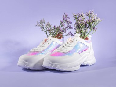 Mor arka planda çiçekli beyaz kadın ayakkabıları. Bahar mevsimi moda kavramı.