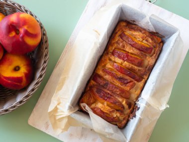 Ev yapımı vejetaryen şeftali turtası turkuaz yeşil bir açık hava masasında pişirme kalıbında. Yaz tatlı tatlı tatlı mevsimlik meyveler, üst manzara, yakın çekim