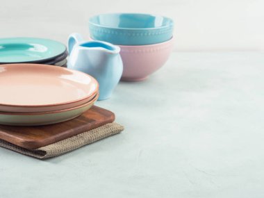 Şık ve zarif pastel renkli sofra takımı ve ahşap kesme tahtaları. Turkuaz arka planda yemek takımı