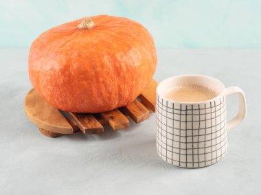 Turkuaz arka planda turuncu kırmızı kuri hokkaido kabaklı balkabağı aromalı latte kahve. Sonbahar sıcak içkisi