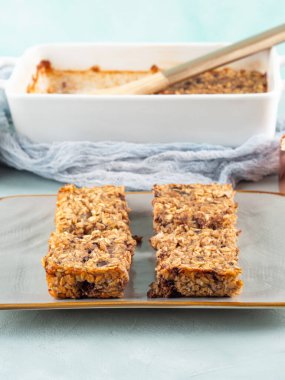 Gri tabakta muzlu vejetaryen yulaf ezmeli kek. Sağlıklı kahvaltı, rulo yulaf, muz, fıstık ezmesi, soya sütü ve çikolata parçacıklı yulaf lapası.