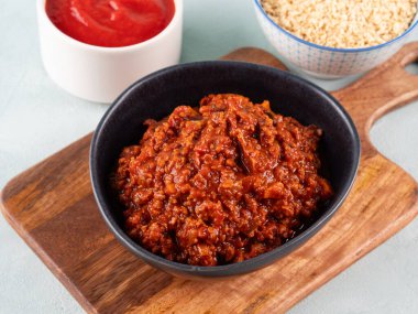 Turkuaz arka planda tahta tahtada soya proteini granülleriyle vejetaryen domates yahnisi ragusu. Makarna yerine soya sosu.