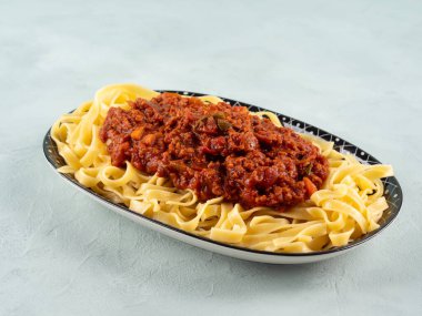 Tagliatelle makarnası vejetaryen domates bolonez ragu ve turkuaz arka planda soya protein granülleri..
