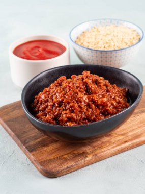 Turkuaz arka planda tahta tahtada soya proteini granülleriyle vejetaryen domates yahnisi ragusu. Makarna yerine soya sosu.