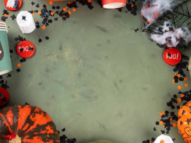 Cadılar Bayramı yeşil arka planda balkabağı ve parti dekoruyla düzüşme. Tatil çocukları içki niyetine şeker ve fincanlarla parti konsepti