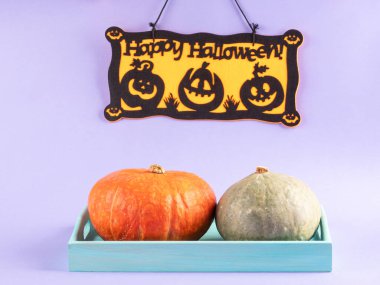 Halloween party decor with greetings of happy holiday with pumpkins on purple background