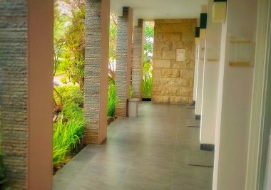 Sütunlarında beyaz taş süslemeler olan otel terası. Doğal taşlar bir binanın dekorasyonuna değer katmak için çok güzeldir. Yeşil bahçeyle birleştirilmiş..