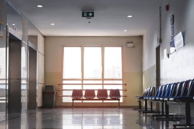 Akşam güneşi cam pencerelerden parlıyor boş sandalyelere ve hastanenin dinlenme yerindeki koridorda asansörlere. 