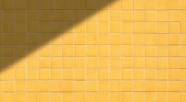 Geniş ekran görünümünde ışık ve gölgeli sarı kare kiremit duvar deseni arkaplanı