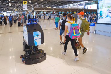 Samut Prakan, Tayland - 03 Aralık 2022: Otomatik zemin temizleme robotu Suvarnabhumi Havalimanı terminalinde bir çok yolcu yürürken